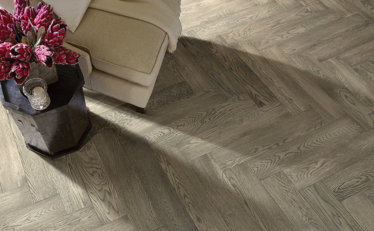 Herringbone hardwood floor with beige chair.